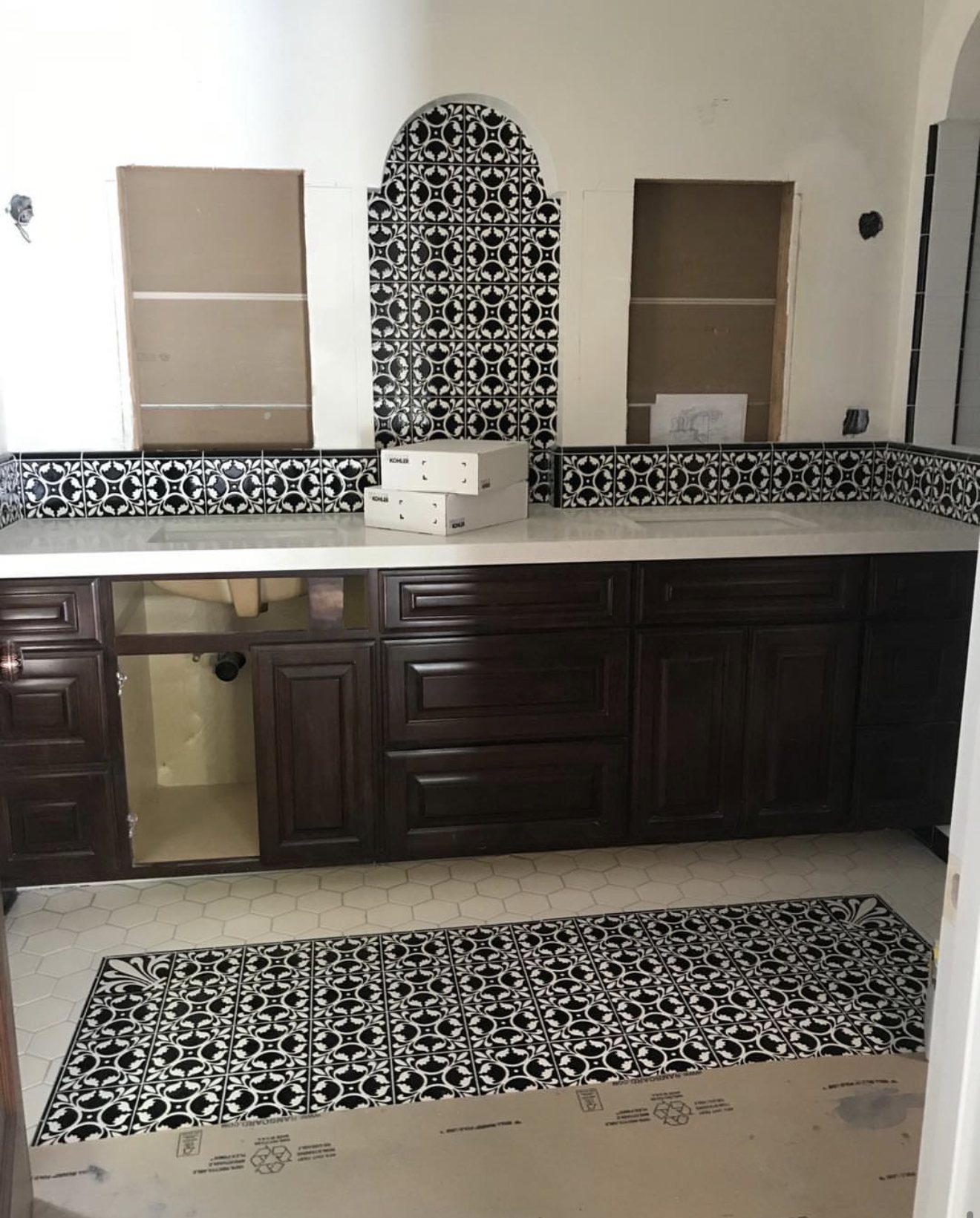 Double vanity with an arched black-and-white cement tile niche and a matching floor rug inset