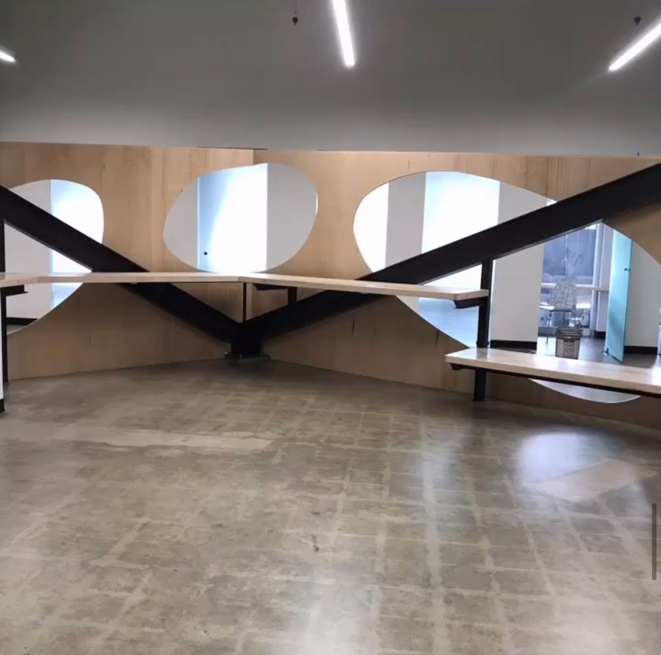 Ad Astra School learning space with black steel beams and birch plywood walls with oval cutouts