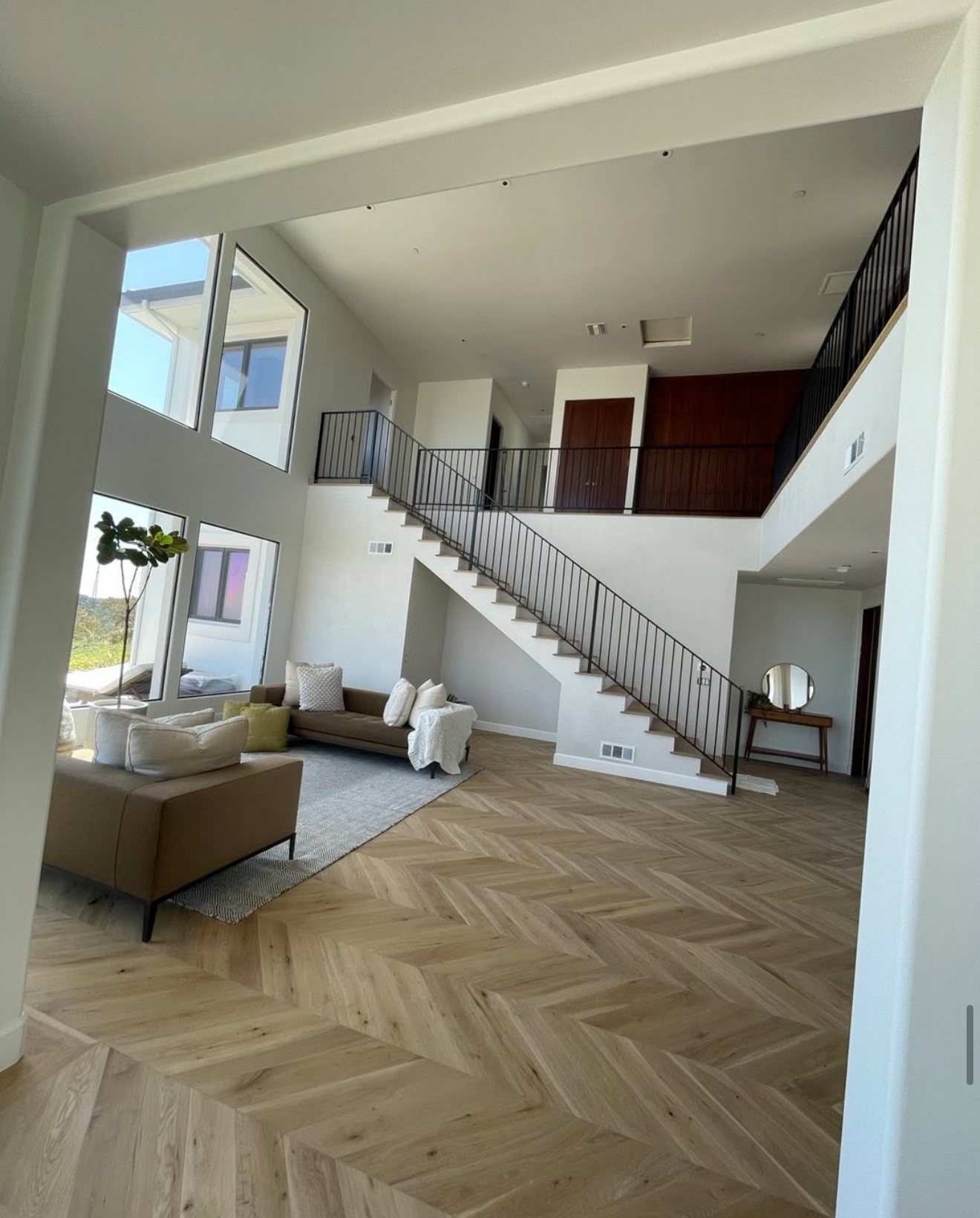 Double-height living room with chevron oak floors and a steel-railed stair