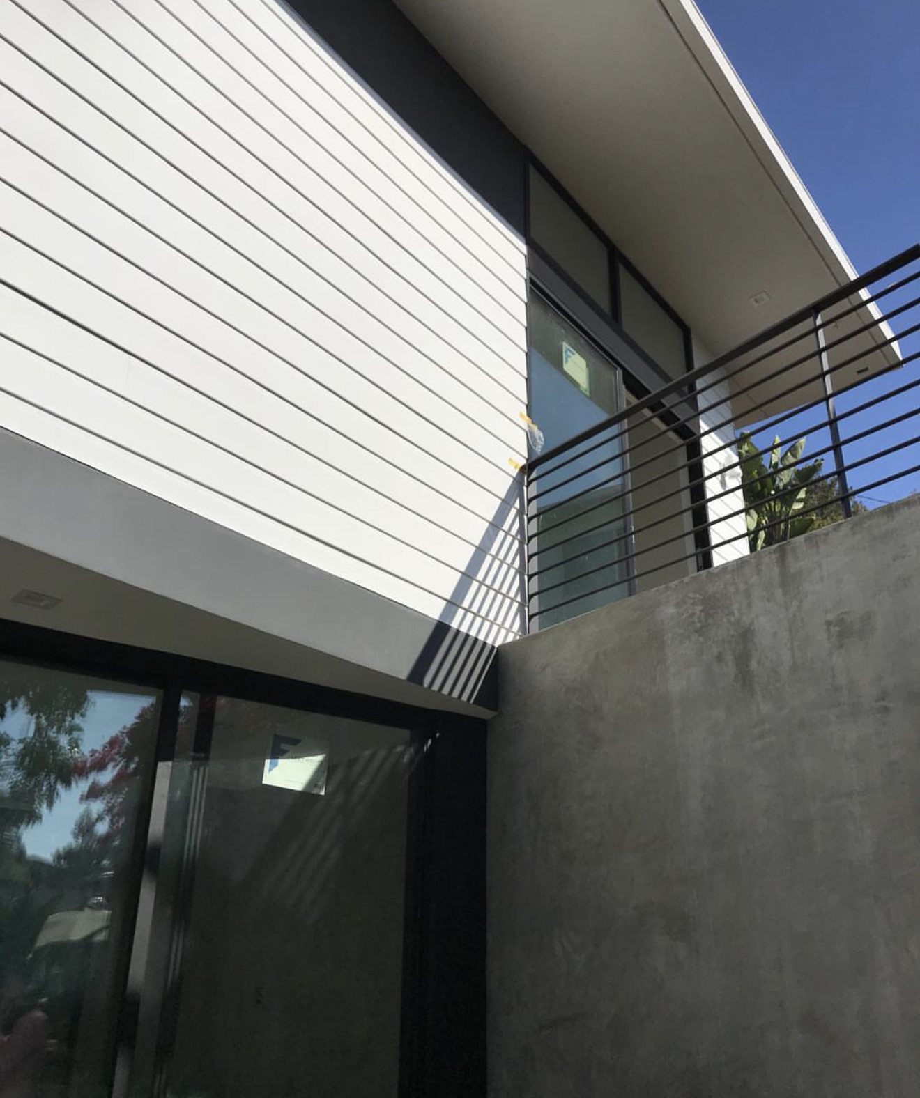 Modern exterior with white lap siding, black window frames, and a horizontal steel railing