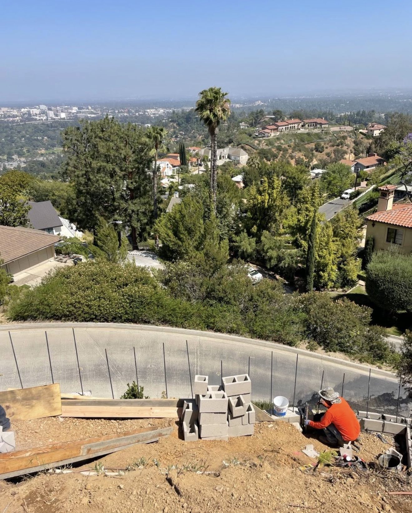 Crew building a block retaining wall on a hillside lot