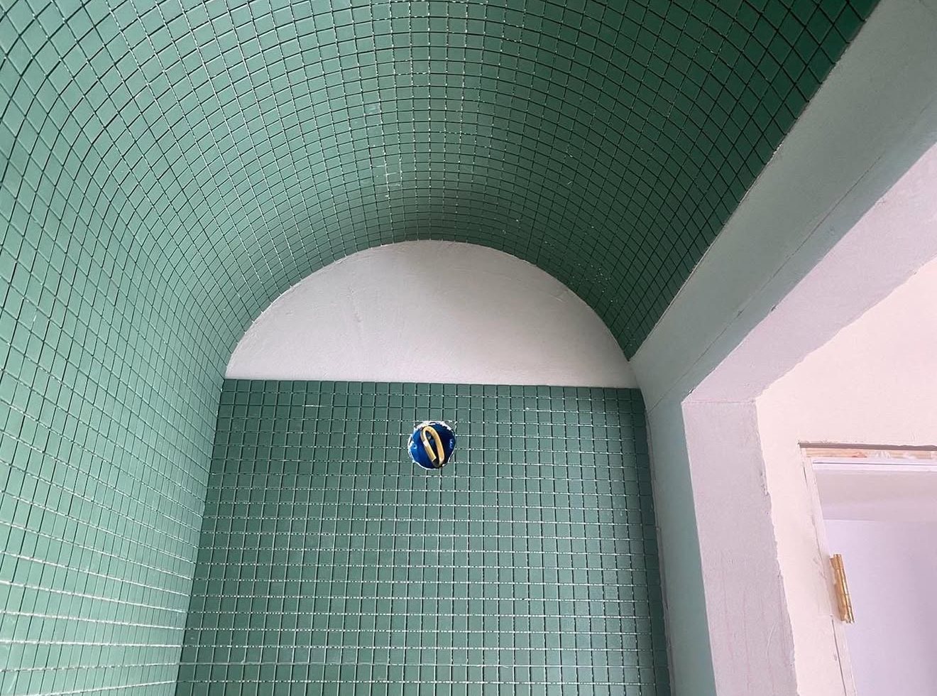 Shower with a barrel-vaulted ceiling in green mosaic tile