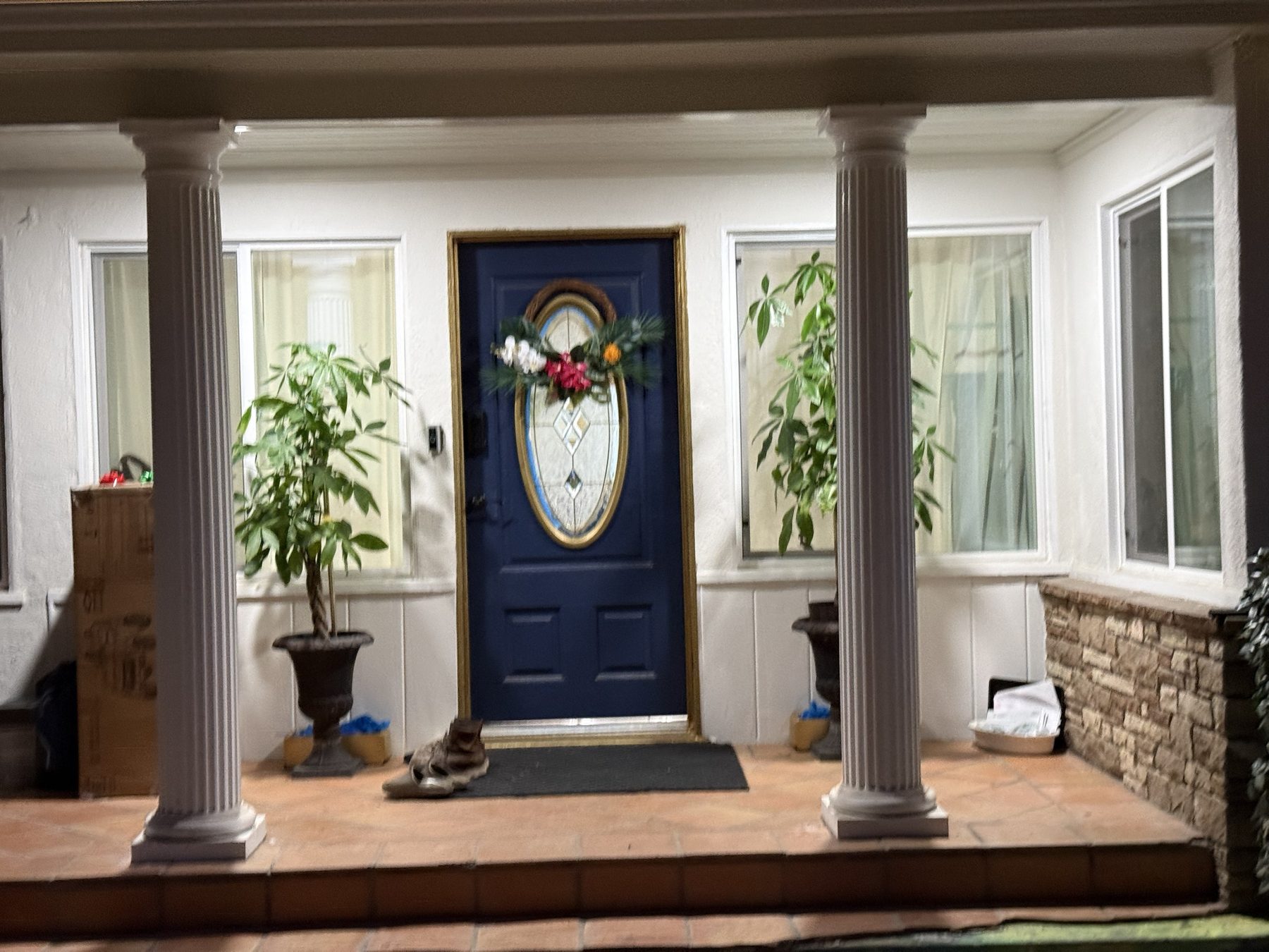 Finished front porch with white columns, a navy door with gold trim, and terracotta tile