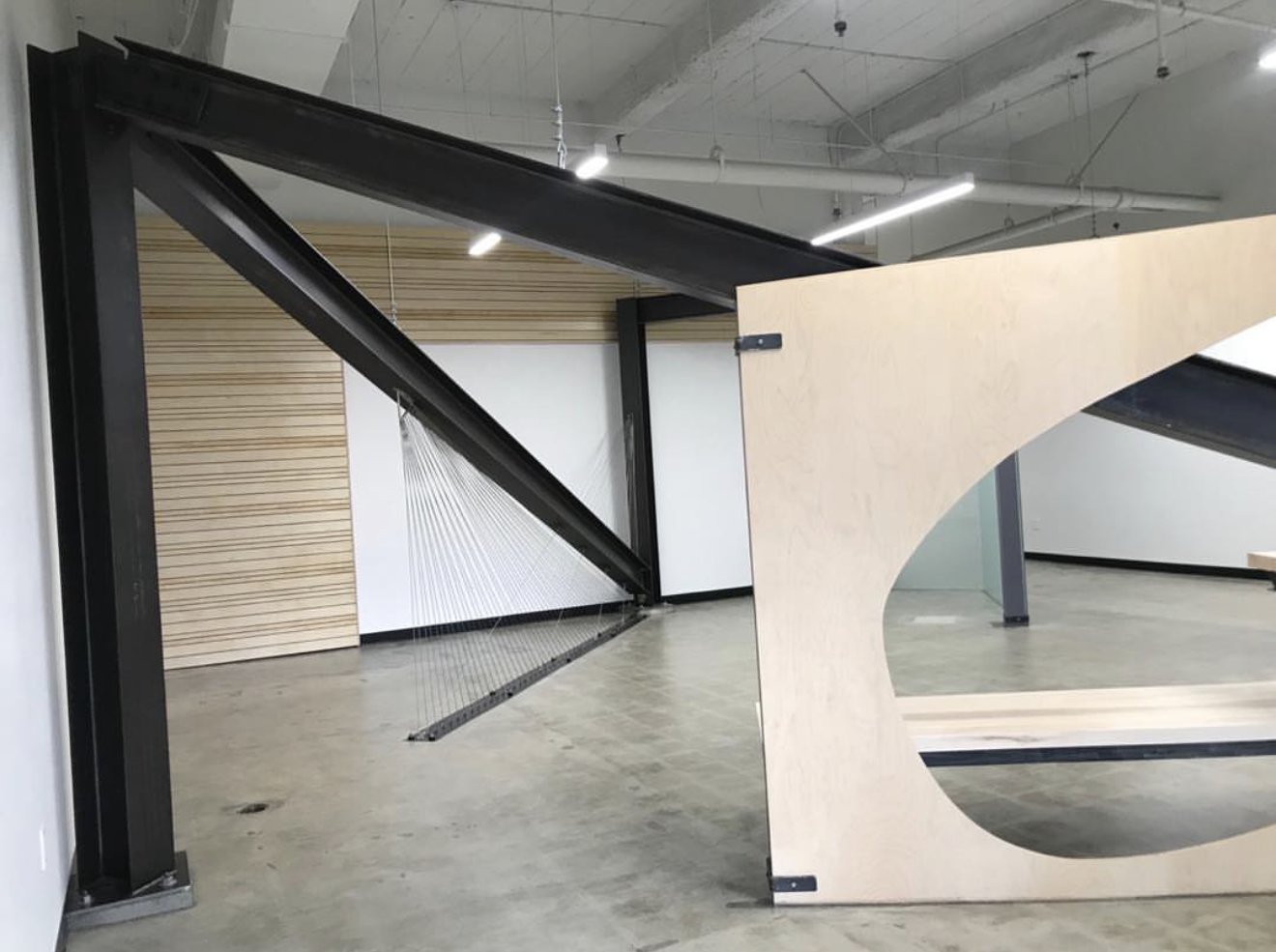 Ad Astra School interior with black steel beams and a curved birch plywood partition